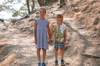 Kids travelers holding hands in mountains and look camera. travel and hiking summer vacation