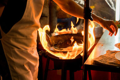 Midsection of chef preparing food in commercial kitchen