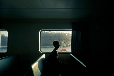 Side view of man sitting by window at bot