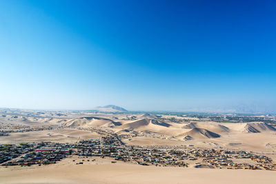 Scenic view of desert landscape against clear blue sky at huacachina