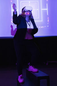 Smiling young businesswoman wearing virtual reality glasses gesturing in workshop