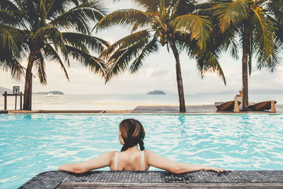 Rear view of woman relaxing in swimming pool