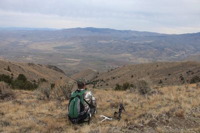 Rear view of man sitting against mountains