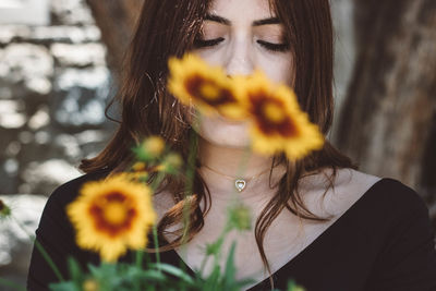 Young beautiful woman behind yellow flowers