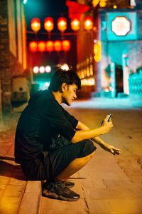 Side view of man using mobile phone at night