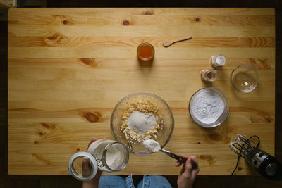 Top view of a young woman making christmas cookies on a wooden table