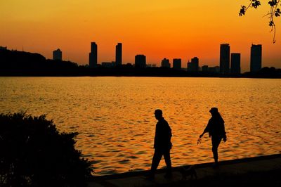 Silhouette people walking by the river