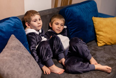 Siblings sitting on sofa at home