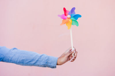 Close up of woman holding colorful pinwheel. pink background,wind energy