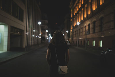 Rear view of woman standing on street at night