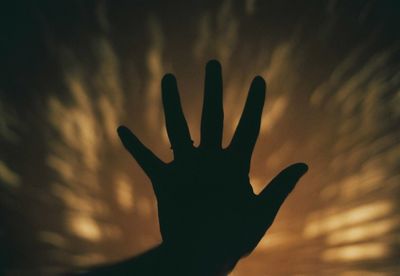 Close-up of silhouette hand against blurred background