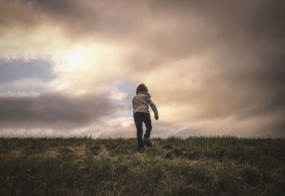 Rear view of man standing on field against sky