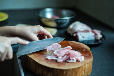 Cropped hands of woman cutting fish on wood