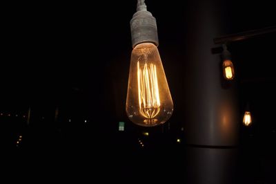 Low angle view of illuminated light bulb against black background