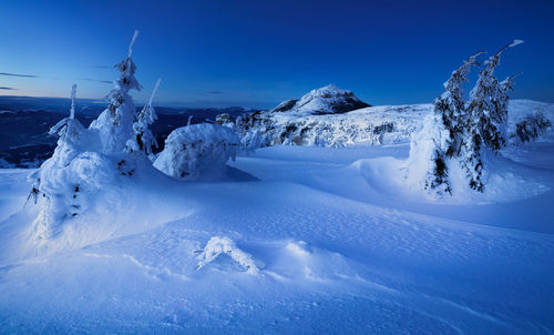 Scenic view of snow covered mountains against blue sky