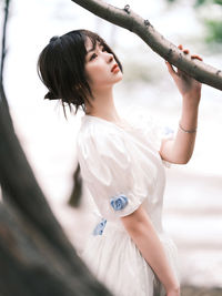 Young woman looking away while standing against blurred background