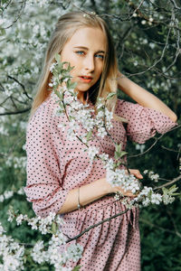 Blonde girl on a spring walk in the garden with cherry blossoms. female portrait, close-up. 