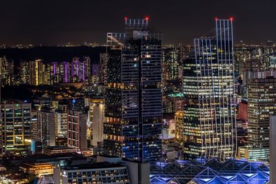 Illuminated modern buildings in city against sky at night
