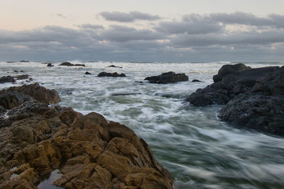 Rocks on sea shore against sky
