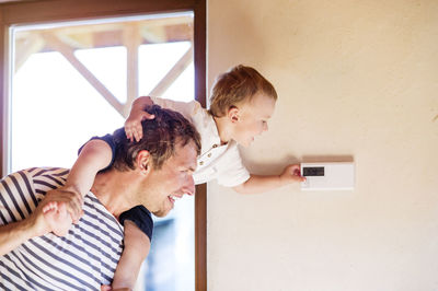 Father and son against wall at home