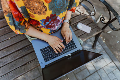 Female hands working on her laptop while sitting on park