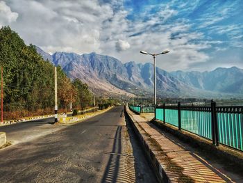 Road by mountains against sky