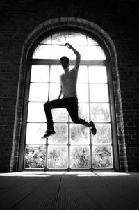 Full length of man jumping against window