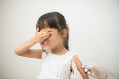 Cropped hands of doctor injecting girl against white background