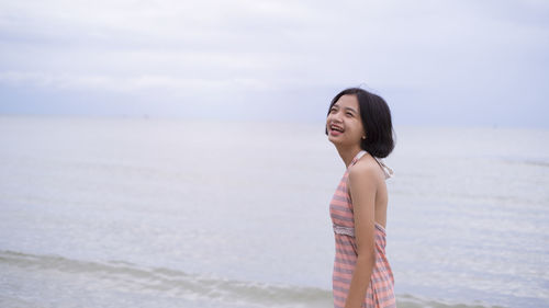 Woman standing at beach against sky