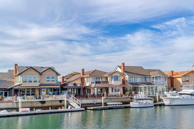 Buildings by river against sky