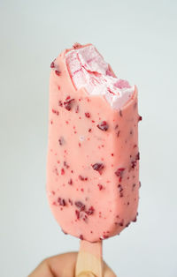 Close-up of hand holding ice cream against white background