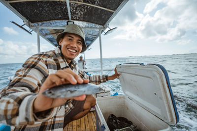 Low angle view of woman holding boat in sea against sky