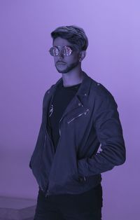 Portrait of young man standing against gray background