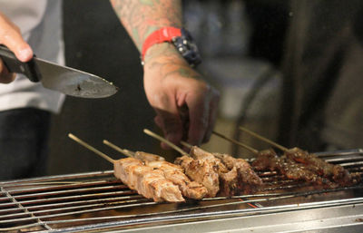 Close-up of man preparing food on barbecue grill