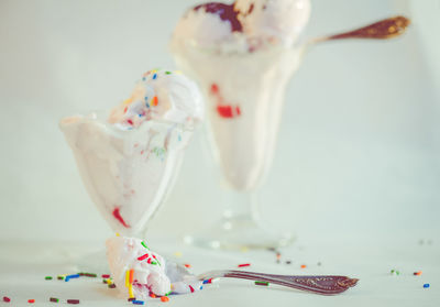 Delectable ice cream in glasses with sprinkles all over the table