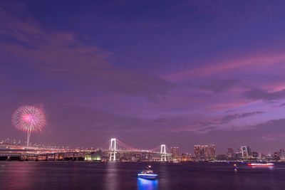 Rainbow bridge in tokyo at night with fireworks.