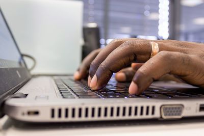 Cropped hands of person using laptop