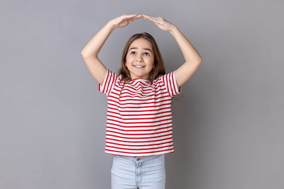 Portrait of young woman standing against wall