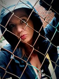 Portrait of young woman standing by fence