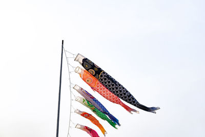 Multi colored flags hanging against white sky