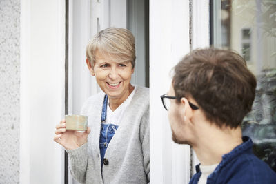 Smiling mature woman with male colleague at entrance of art studio