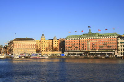 View of buildings by river against clear sky