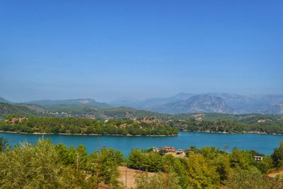 Scenic view of lake and mountains against clear blue sky