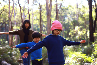 Family with arms outstretched walking in forest