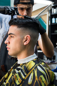 Barber cutting hair of man at salon