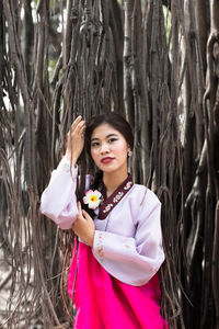 Portrait of woman standing against tree in forest