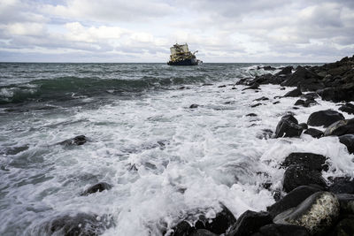 Scenic view of rocks in sea against sky