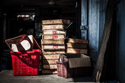 Stack of wooden crates by plastic chair in container in storage room