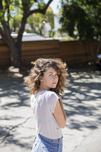 Portrait of woman standing against tree