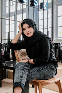 Portrait of young woman sitting on sofa at home